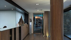 Un área de recepción moderna con un mostrador de madera, una columna cilíndrica grande y un mostrador decorado con un árbol de Navidad.