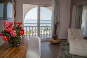 Una habitación con una bañera, un sofá blanco, un jarrón de flores y vistas al mar a través de un ventanal.