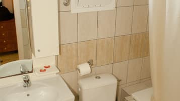 Casa de banho com lavatório, sanita e janela sobre a sanita.