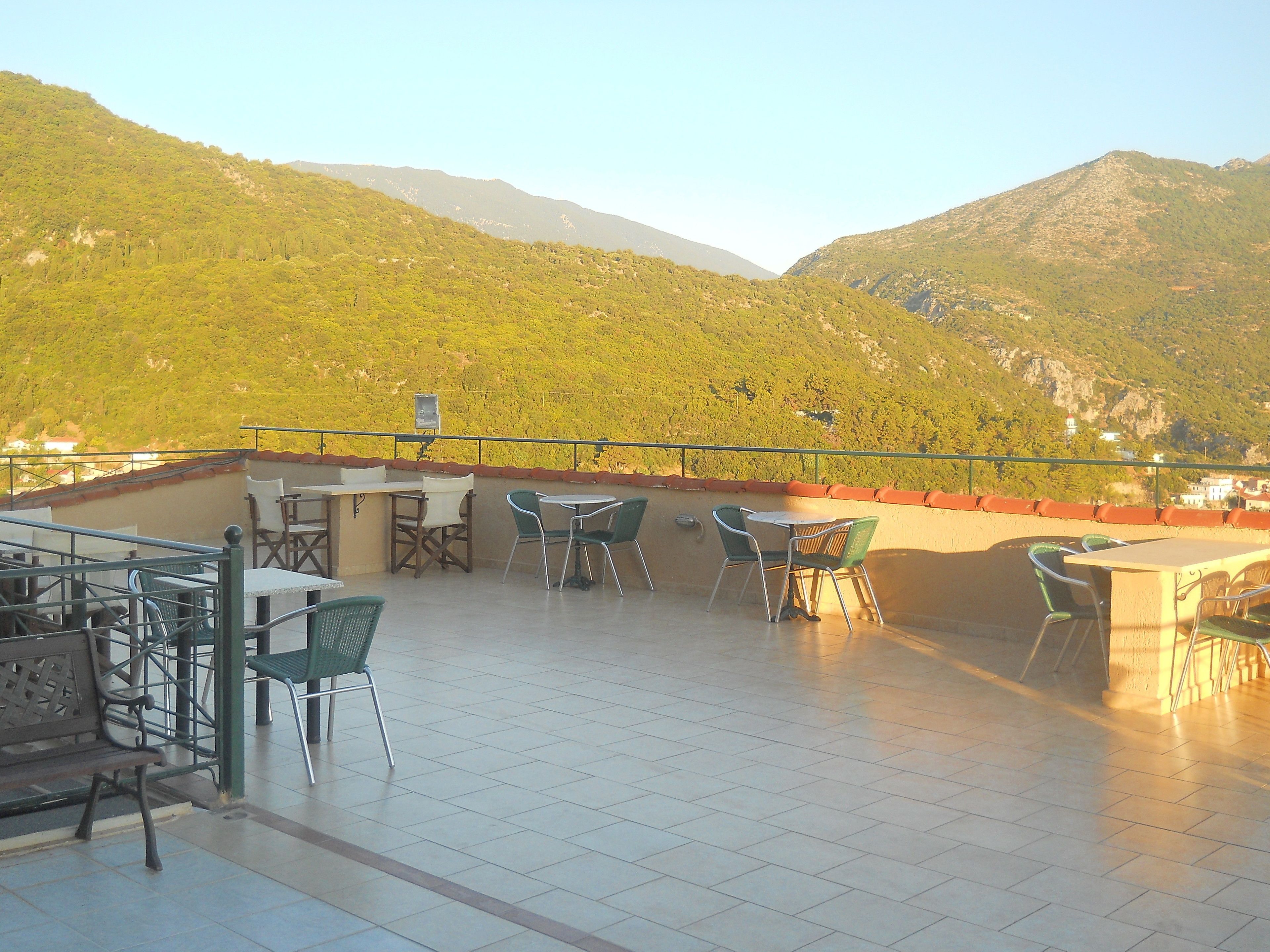 A terrace with tables and chairs, overlooking a mountainous landscape.
