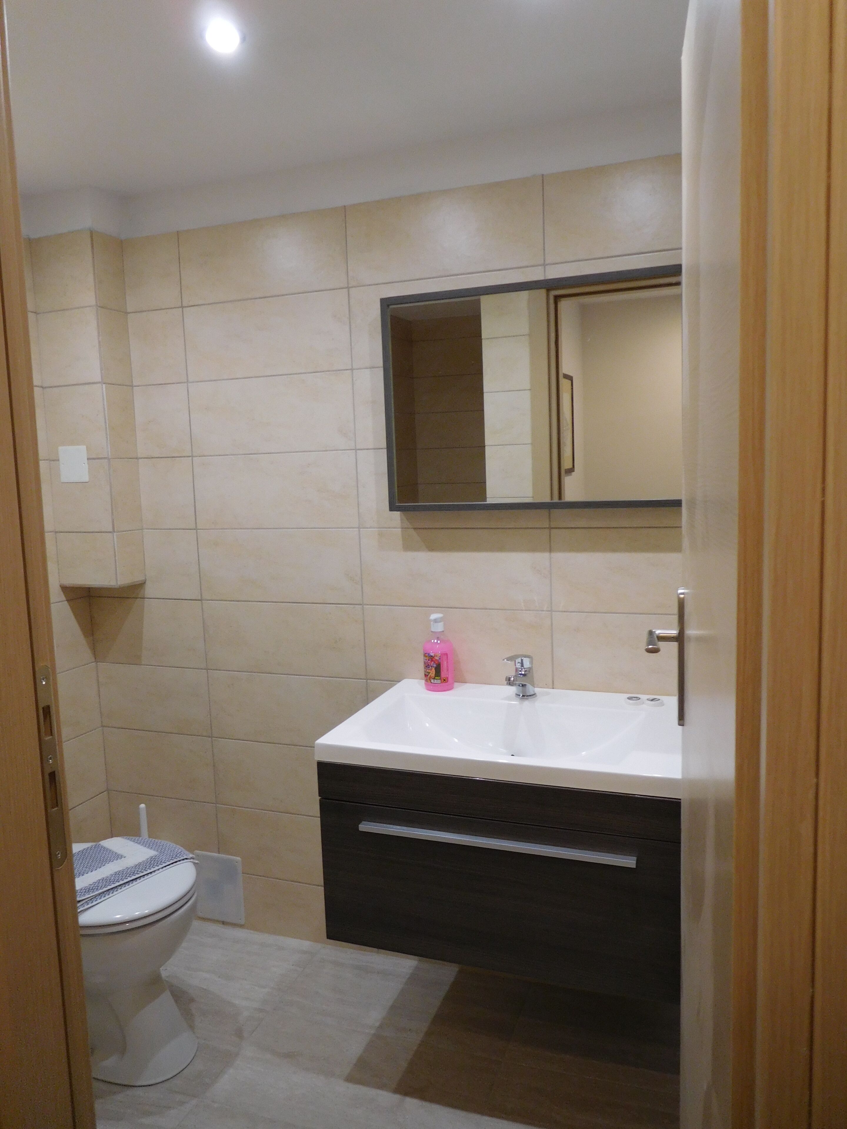 A bathroom with a white sink, a mirror, and a toilet.