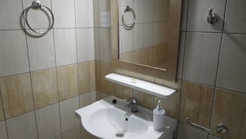 Un baño con lavabo, espejo, toallero y retrete.