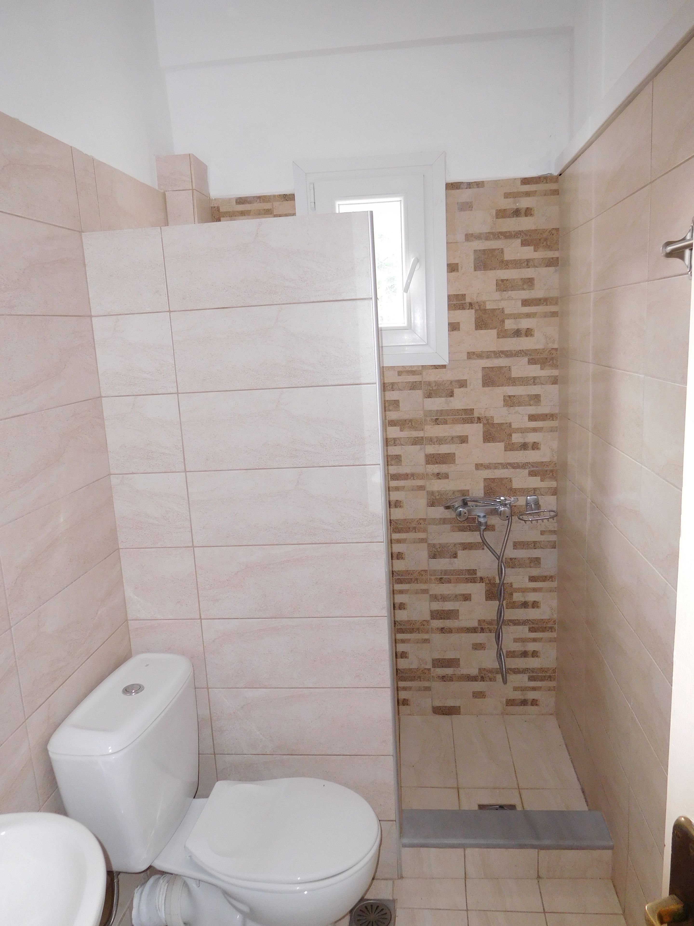 A bathroom with a toilet, a shower, and a window.