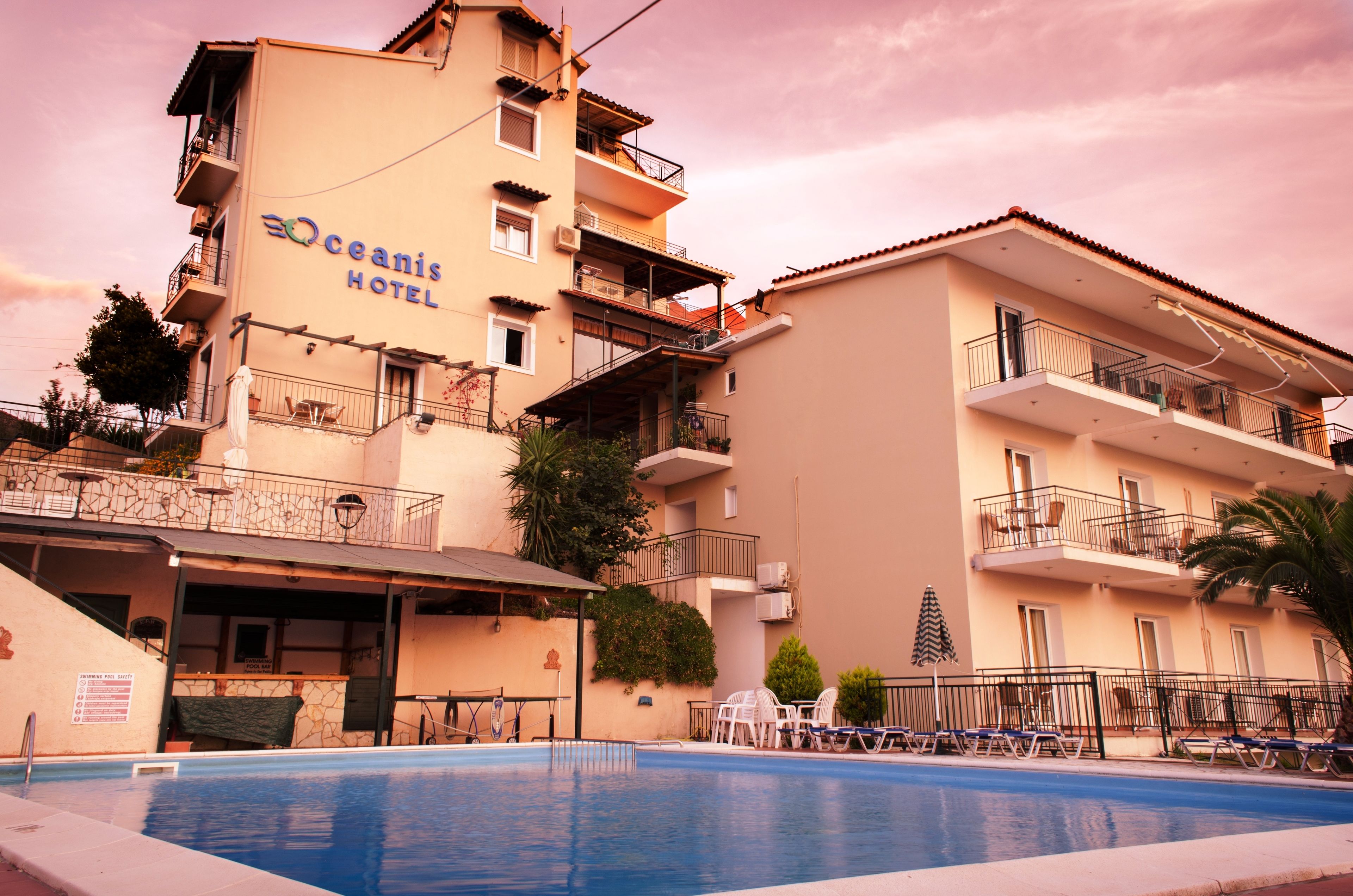 A hotel with a swimming pool, multiple balconies, and outdoor seating.