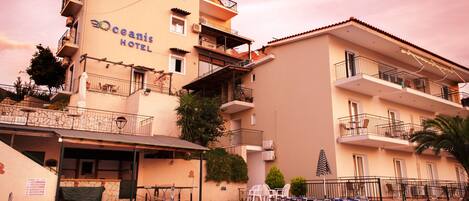 A hotel with a swimming pool, multiple balconies, and outdoor seating.