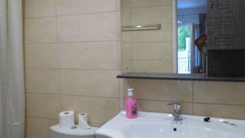 Un baño con lavamanos blanco, espejo e inodoro.