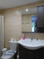 Un baño con lavamanos blanco, espejo e inodoro.