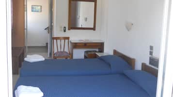 Una habitación de hotel con dos camas, un escritorio de madera, una silla, un espejo y una mesita de noche.