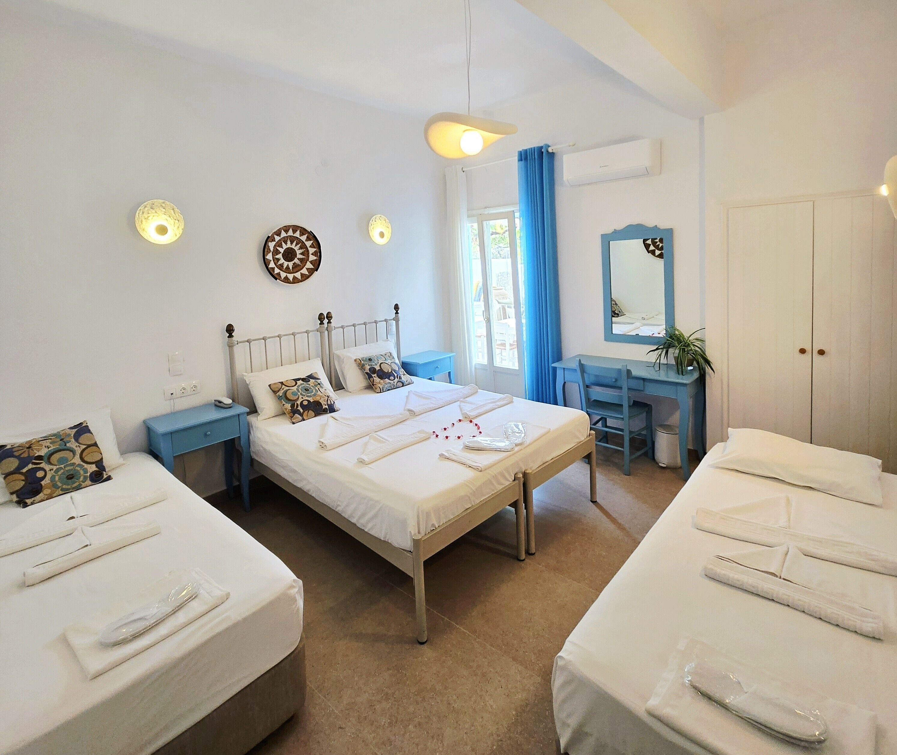 Una habitación de hotel con dos camas, un escritorio, un espejo y una ventana con cortinas.