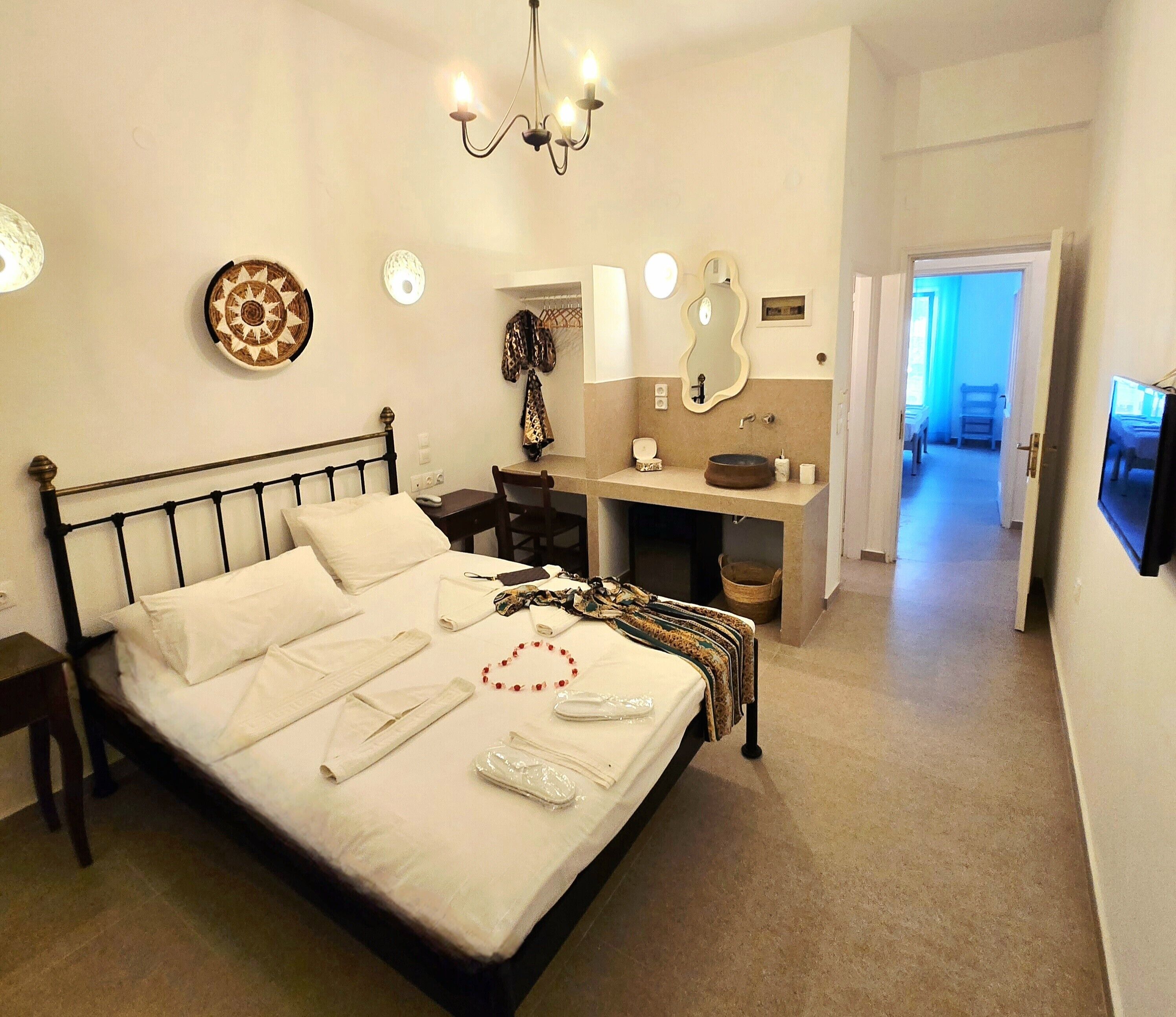 Une chambre d’hôtel comprenant un lit, une table de chevet, une commode, une coiffeuse avec miroir et un téléviseur.