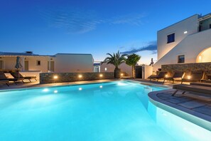 A swimming pool with lounge chairs, a palm tree, and a stone wall.