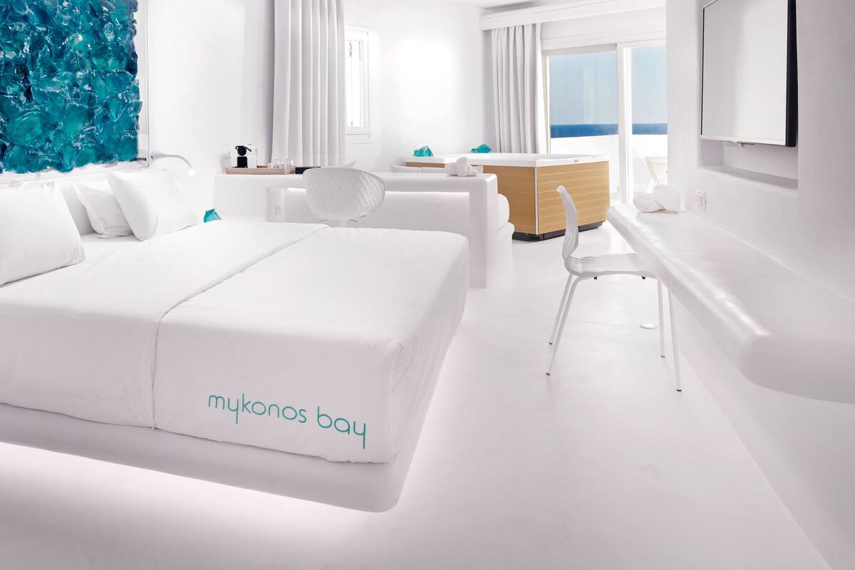 Une chambre d’hôtel moderne avec un grand lit, un bureau et une vue sur l’océan.