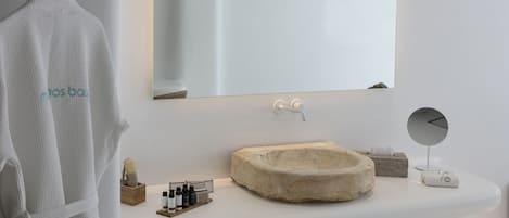 A modern bathroom with a white sink, a round mirror, and a towel rack.