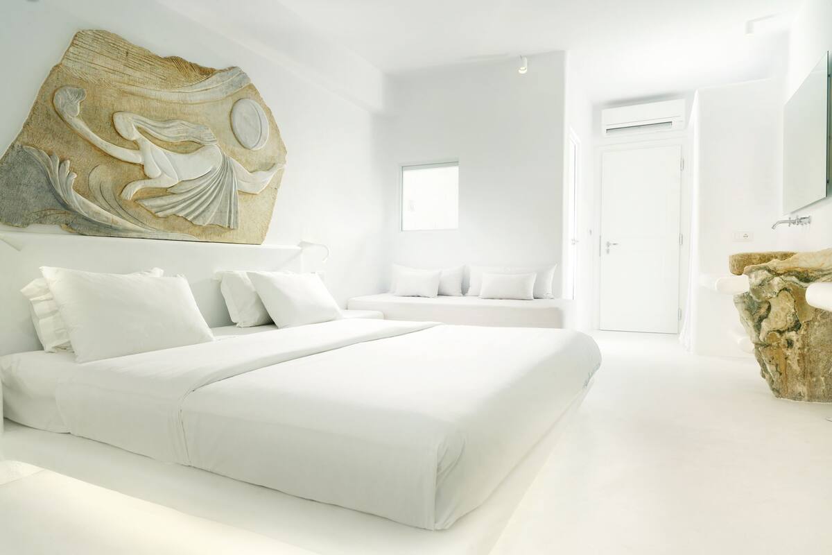 Une chambre à coucher moderne avec un grand lit, une sculpture en pierre et un design minimaliste.