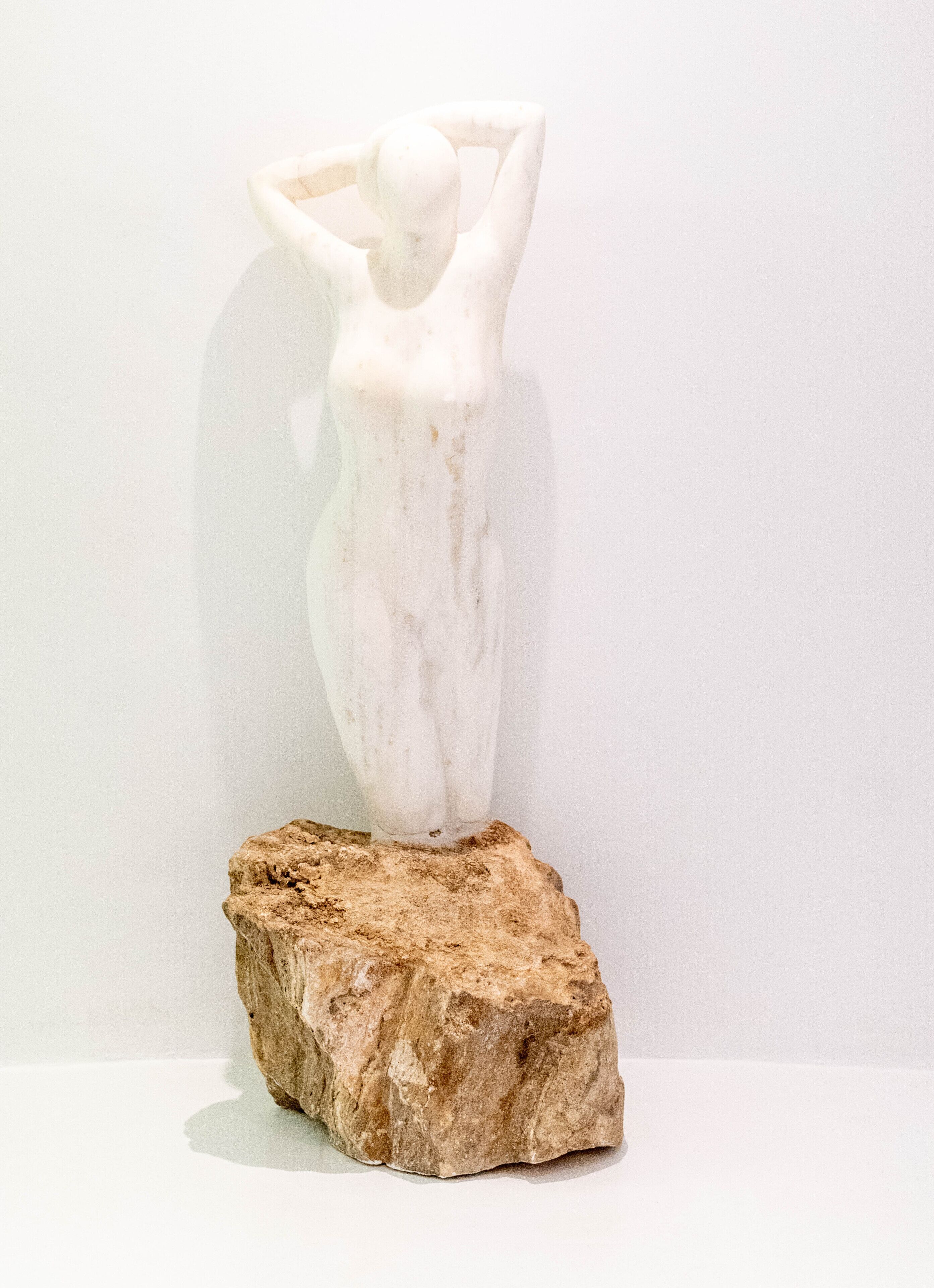A white sculpture on a rough stone base.