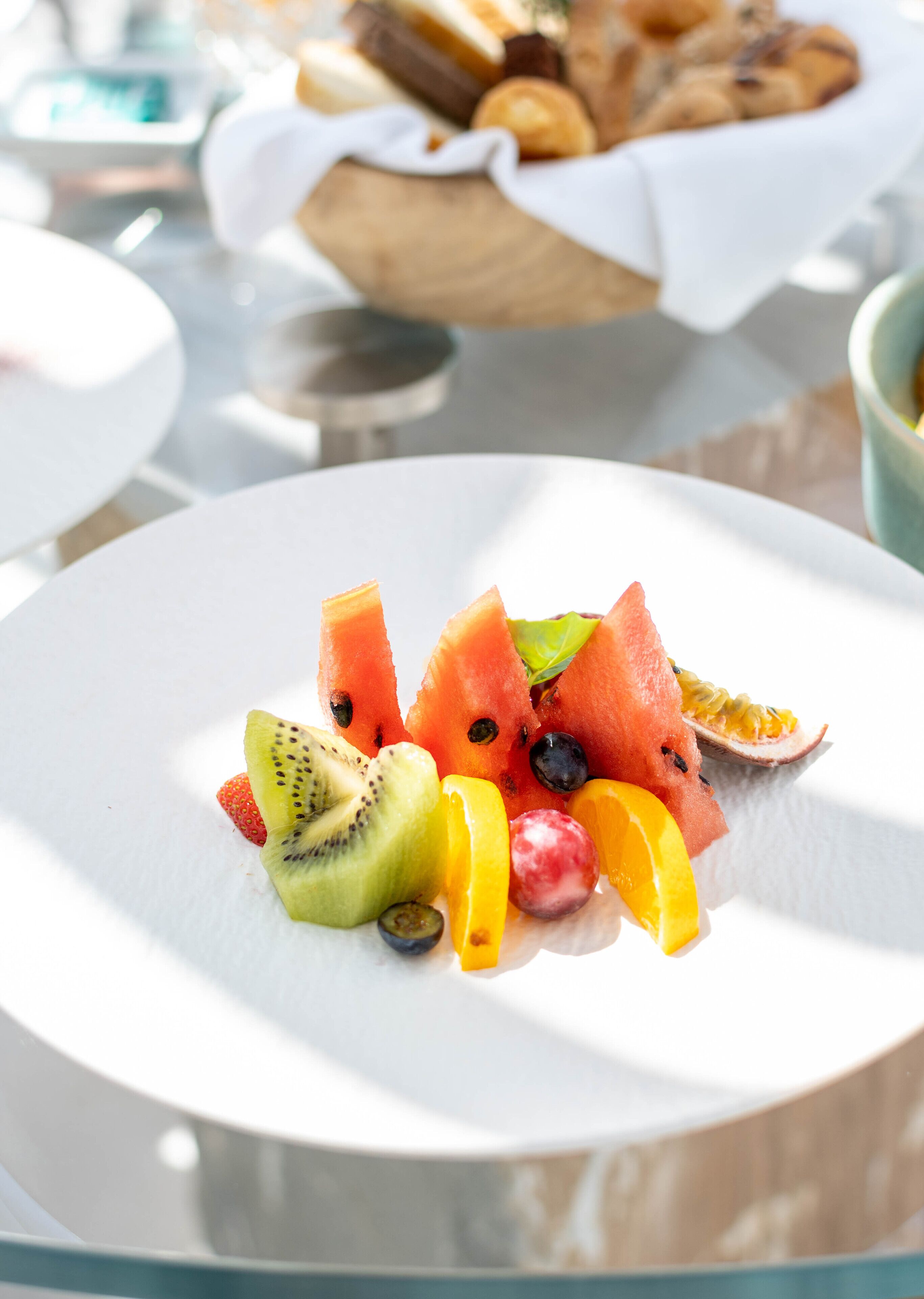 A white plate with assorted fruits including watermelon, kiwi, strawberries, and grapes.