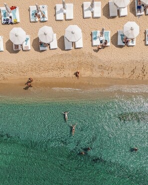 An aerial view of a beach with clear turquoise water, sun loungers, and umbrellas. - Mykonos Bay Resort & Villas (Mykonos)