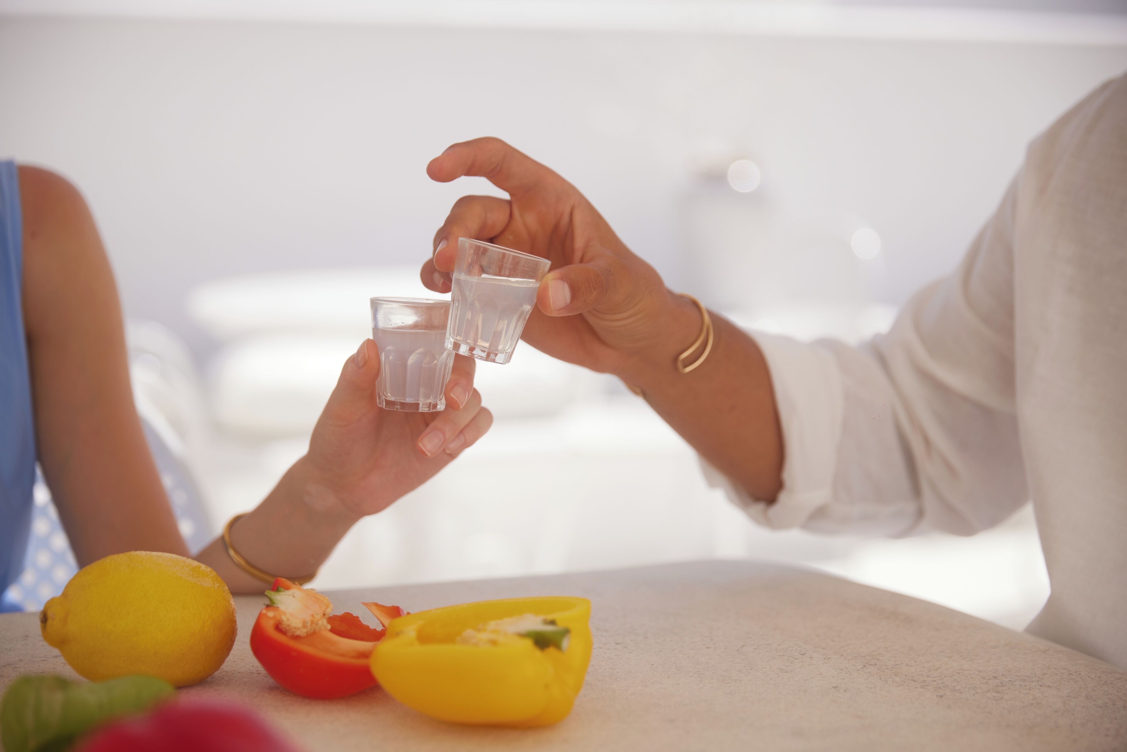 A person pouring a drink from a glass into a smaller glass.