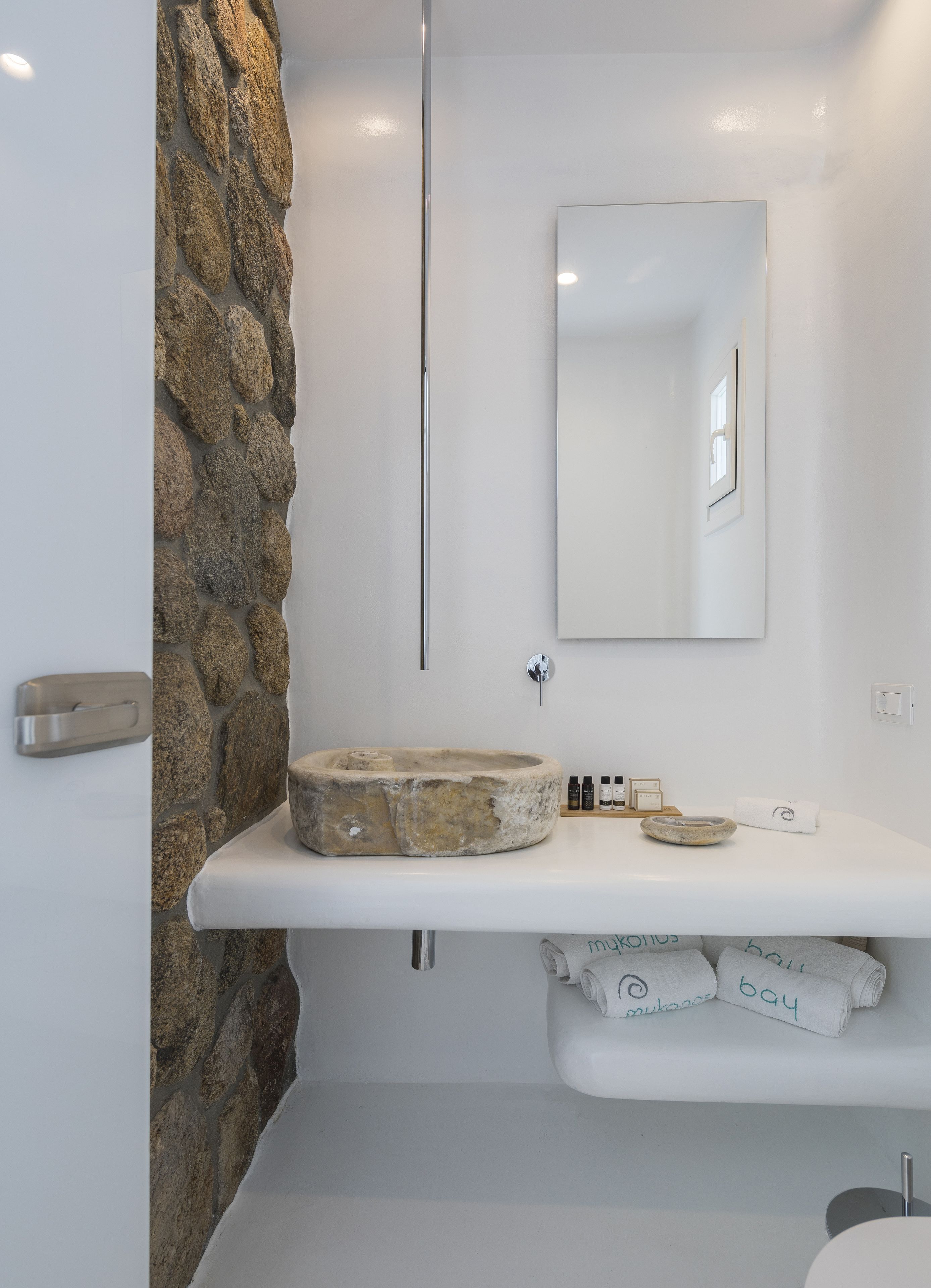 Un baño con un lavabo de piedra, un espejo y un perchero para toallas.