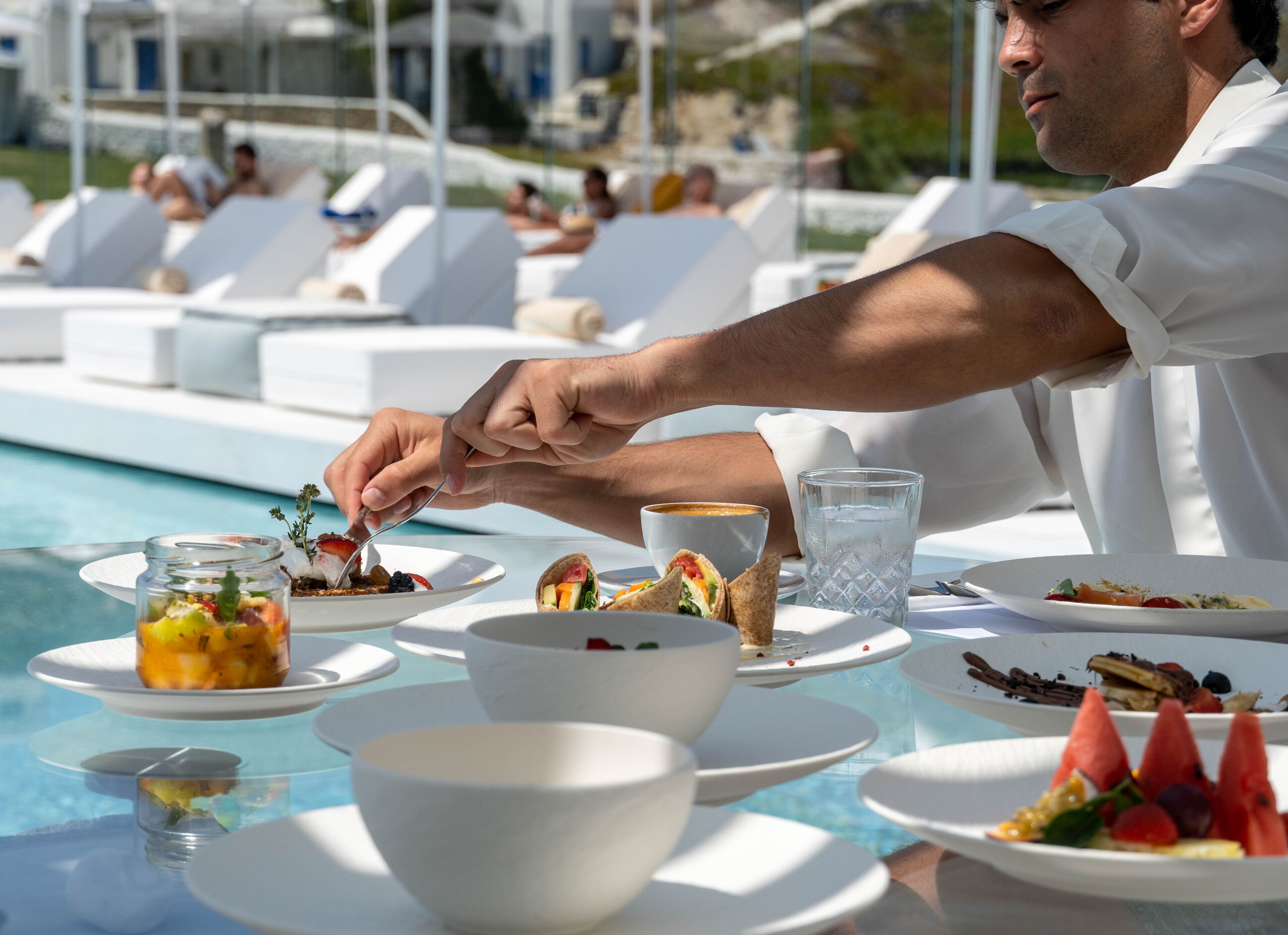 A dining table with plates of food, a glass of water, and a cup of coffee.