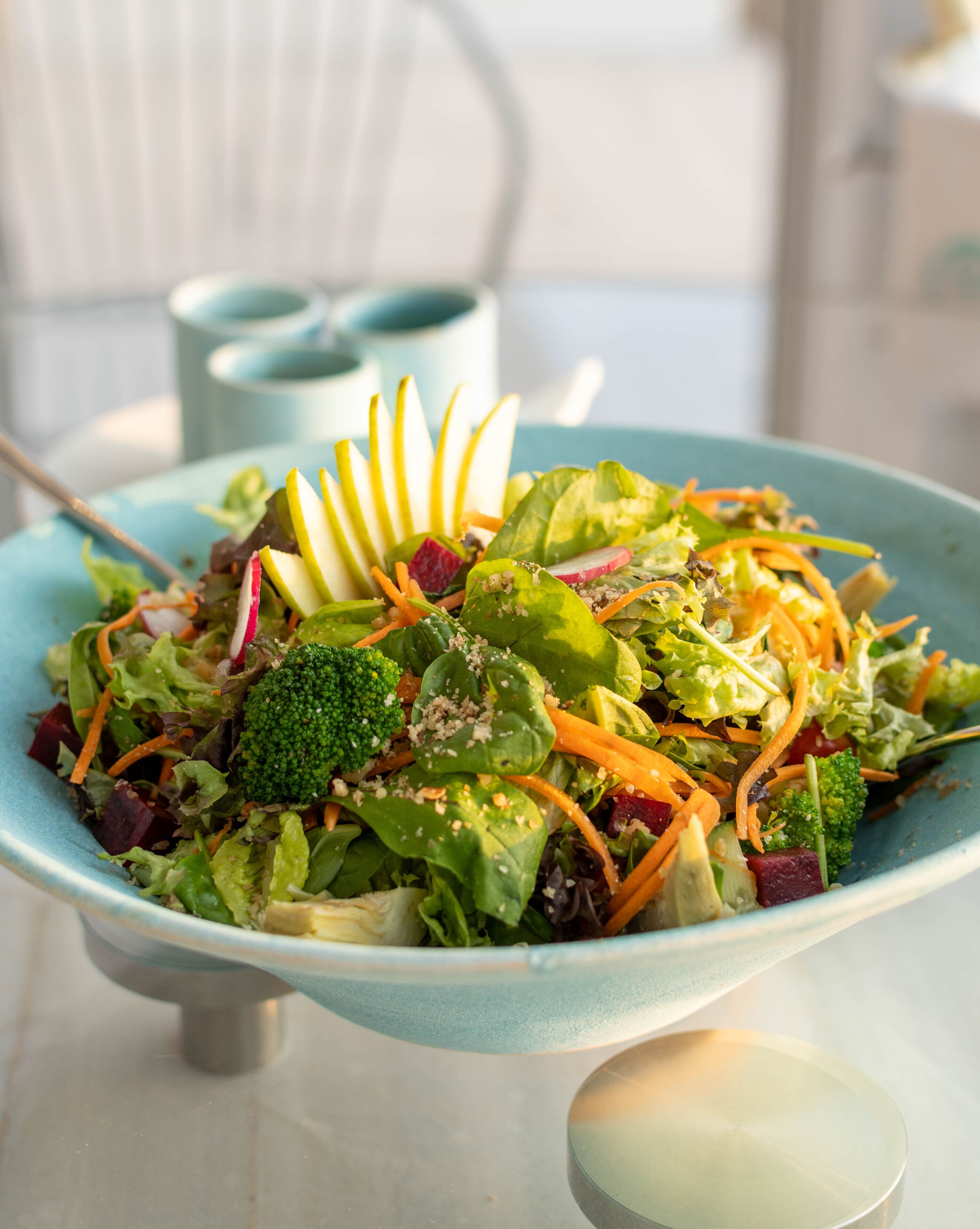 Ensalada en un tazón con diversos vegetales y una rodaja de manzana decorativa encima.