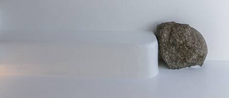 Un relieve que muestra dos figuras: una sosteniendo uvas y la otra recostada, con una roca cerca.