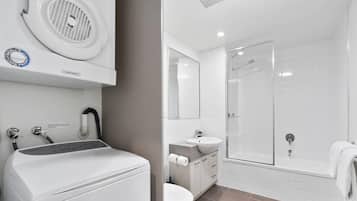 Un baño moderno con inodoro, lavamanos y zona de ducha.