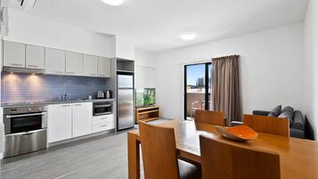 Una cocina moderna con electrodomésticos integrados y un comedor con mesa y sillas de madera.