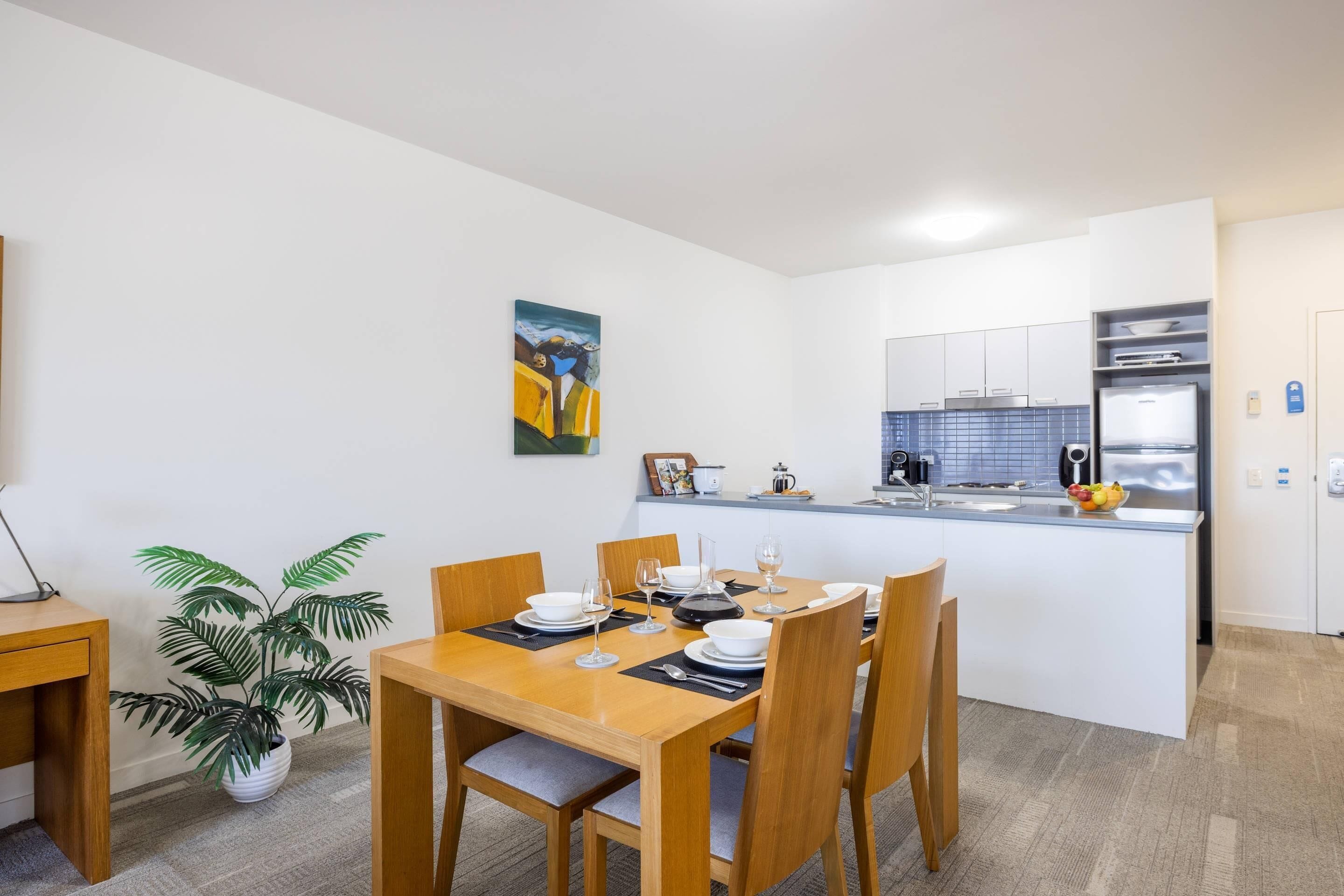 A modern kitchen with white cabinets, a built-in oven, and a countertop with a kettle and fruit bowl.