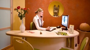 Un mostrador de recepción con un jarrón de flores, una computadora y un letrero que dice "Hotel Rose".