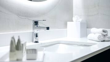 A modern bathroom with a white sink, chrome faucet, and a mirror with a curved frame.