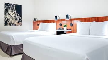 A hotel room with two beds, a wooden headboard, a nightstand, a clock, and a wall-mounted lamp.