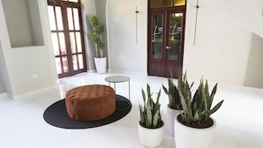 Un intérieur moderne agrémenté d’un pouf rond, d’une petite table ronde et de plusieurs plantes en pot.
