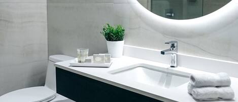 Un bagno moderno con il water bianco, un lavabo con specchio e zona doccia.