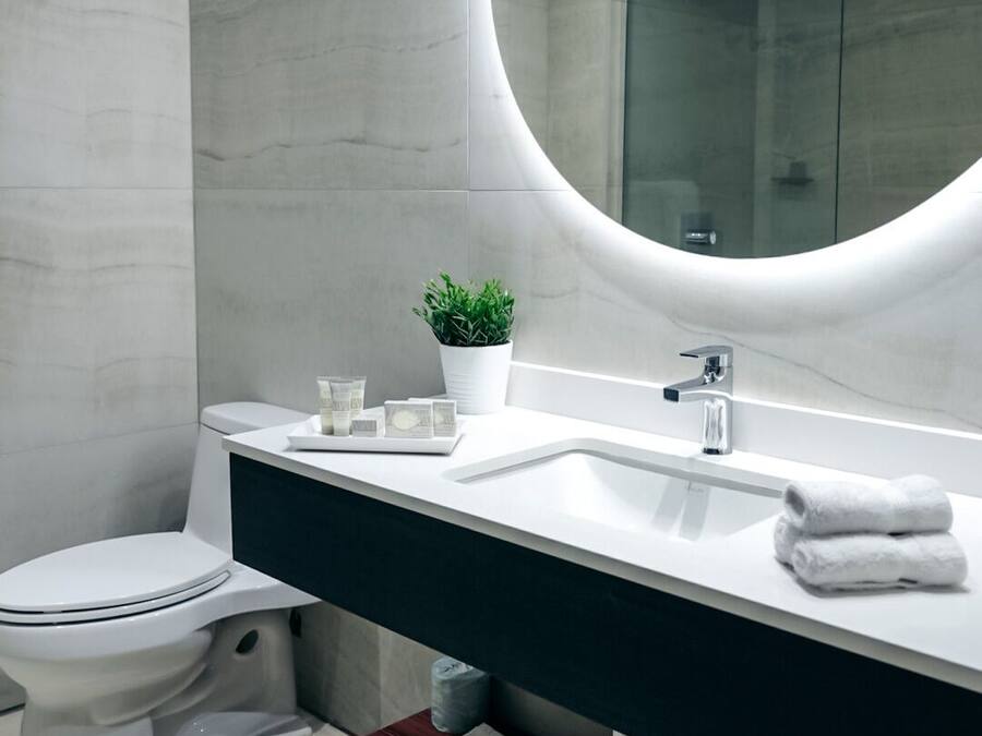 A modern bathroom with a white toilet, a sink with a mirror, and a shower area.