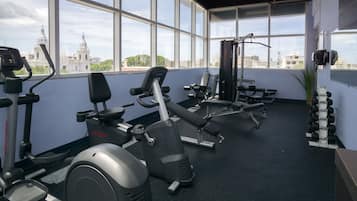 Une salle de sport équipée de machines de cardio, de bancs de musculation et d’haltères.