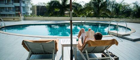 Un área junto a la piscina con sillones de descanso.