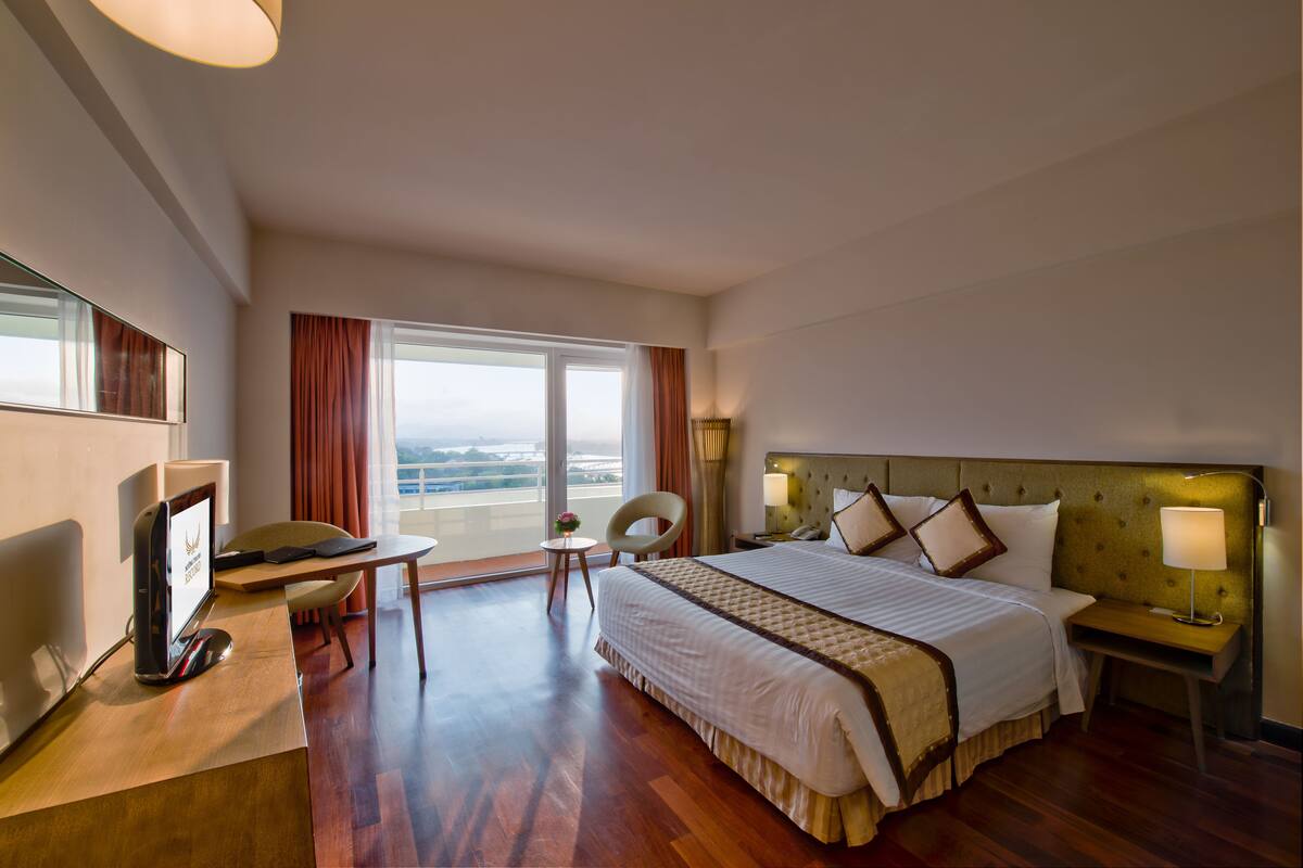 Une chambre d’hôtel équipée d’un lit, d’un bureau, d’une chaise, d’une télévision et offrant une vue sur l’extérieur.