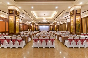 A banquet hall with rows of tables and chairs, a stage, and decorative lighting. - Muong Thanh Holiday Hue Hotel (Hue)