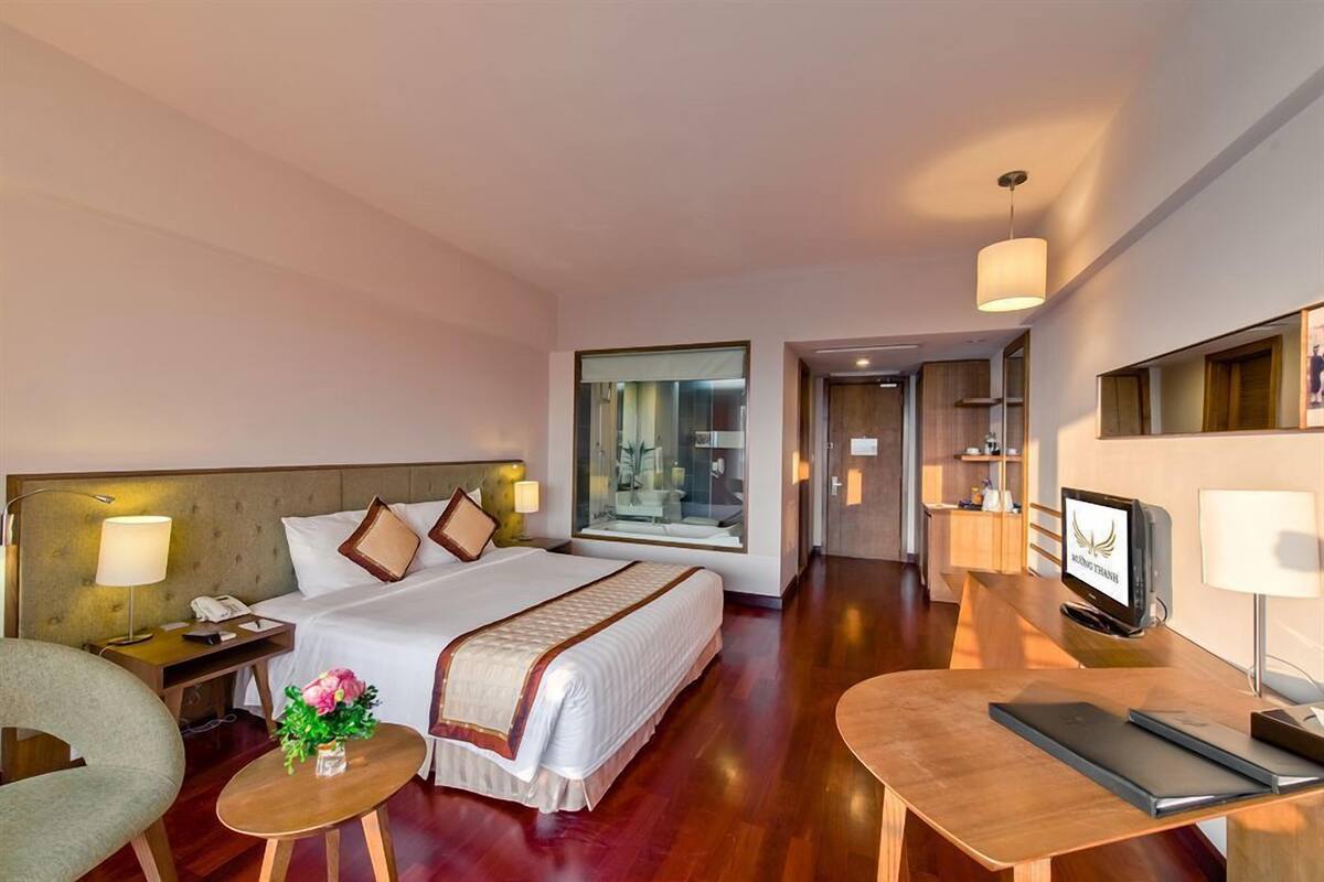 Une chambre d’hôtel comprenant un lit, une table de chevet, une lampe, une chaise, un bureau et un téléviseur.