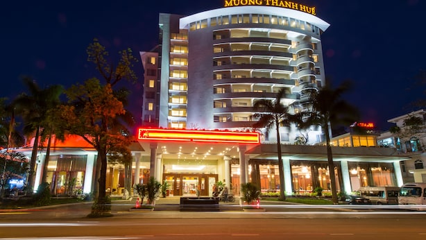 Un hôtel reconnaissable à son enseigne bien visible indiquant « MUONG THANH HUE » et à son architecture moderne, avec plusieurs étages et des balcons.