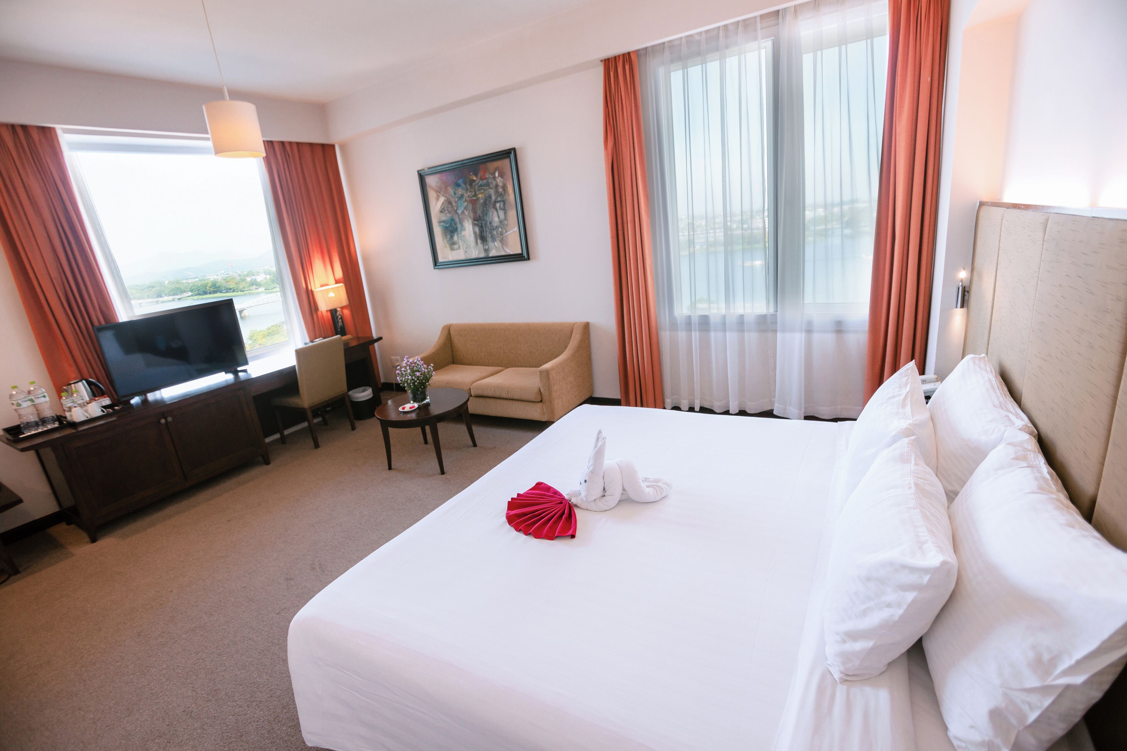 A hotel room with a bed, a TV, a desk, and a chair.