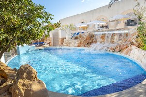 Una piscina al aire libre, sillones reclinables de piscina