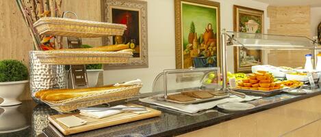 A buffet counter with various food items, wicker baskets, and a decorative wall with framed artwork.