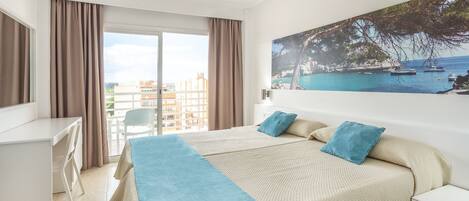 Una habitación de hotel con una cama, un escritorio y vista al mar.
