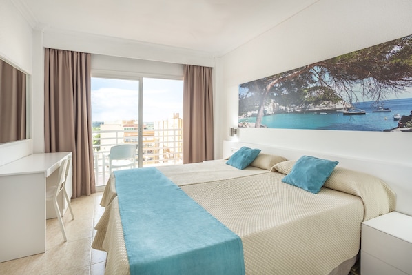 Una habitación de hotel con una cama, un escritorio y vista al mar.