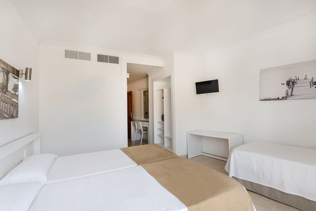 Quarto de hotel com duas camas, uma escrivaninha, televisão e um quadro na parede.
