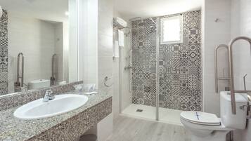 Un baño moderno con lavamanos de granito, ducha con cerramiento de vidrio y un inodoro blanco.