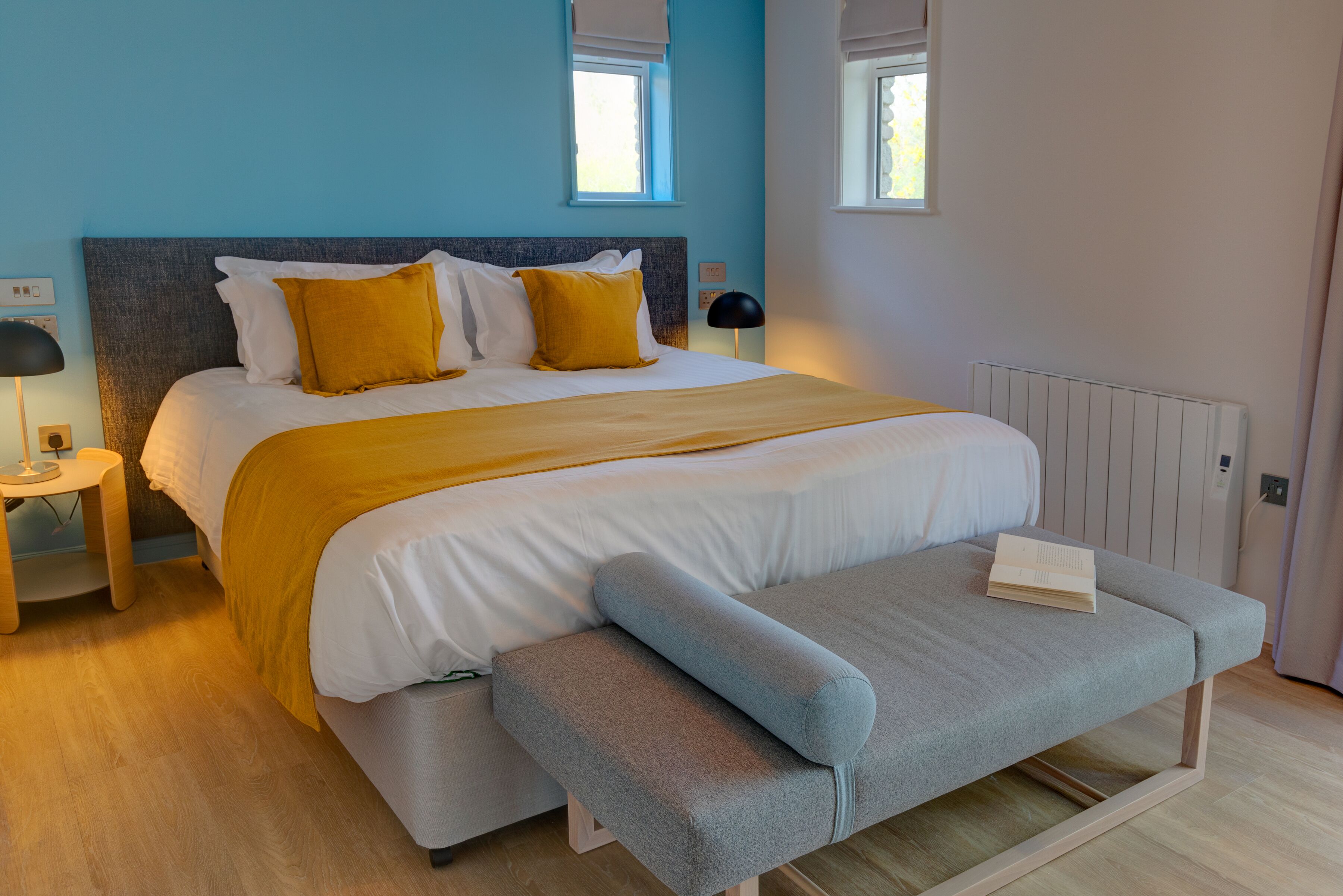 Een moderne slaapkamer met een bed, nachtkastjes en een bankje.