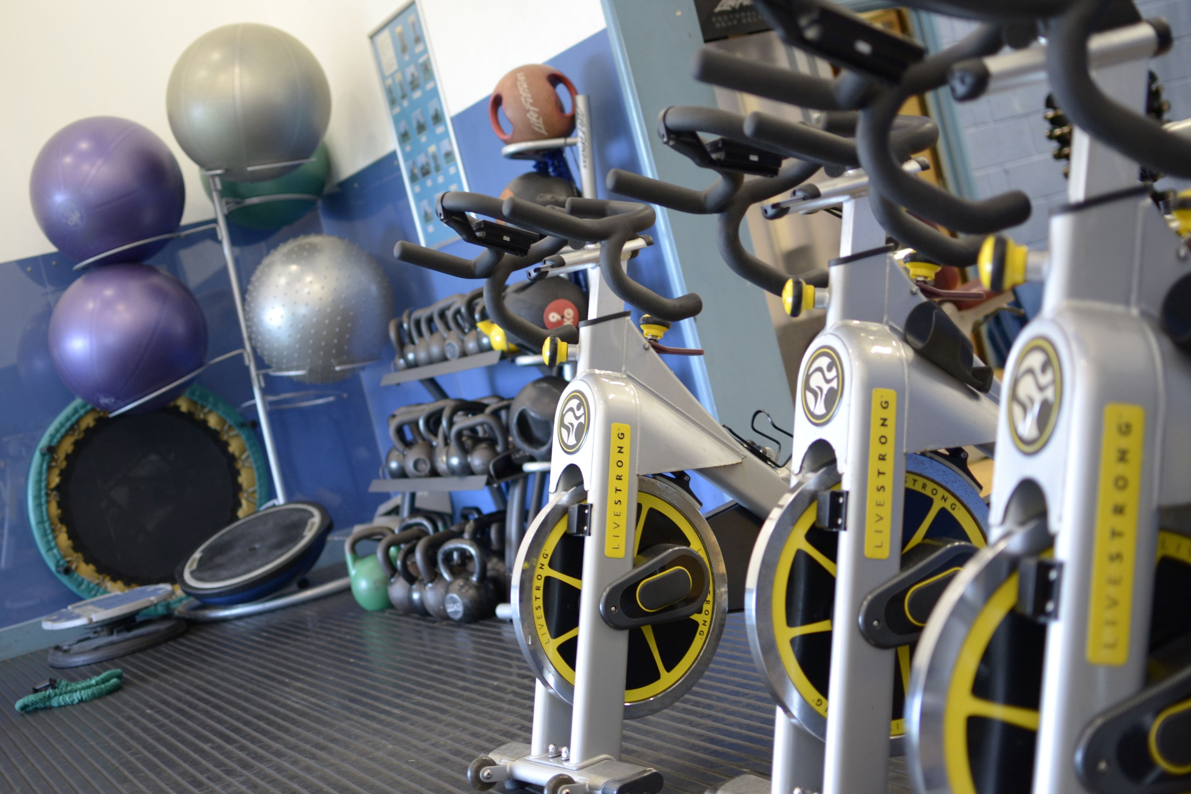 Un gimnasio con equipo de ejercicio, incluyendo cintas de correr, bicicletas estáticas y diferentes pesas.